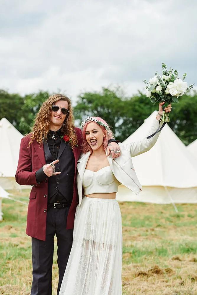 Rock ’n’ roll bride and groom celebrating in front of festival tipis at The Peasantry Brewery, Nottingham