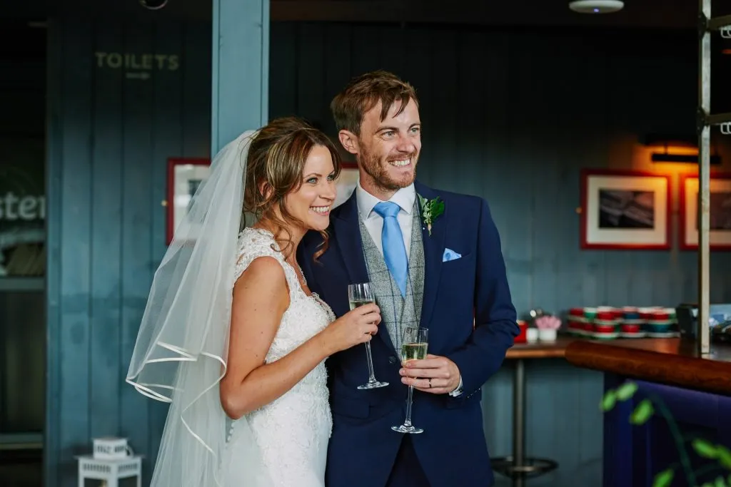 bride and groom smiling and holding champagne 