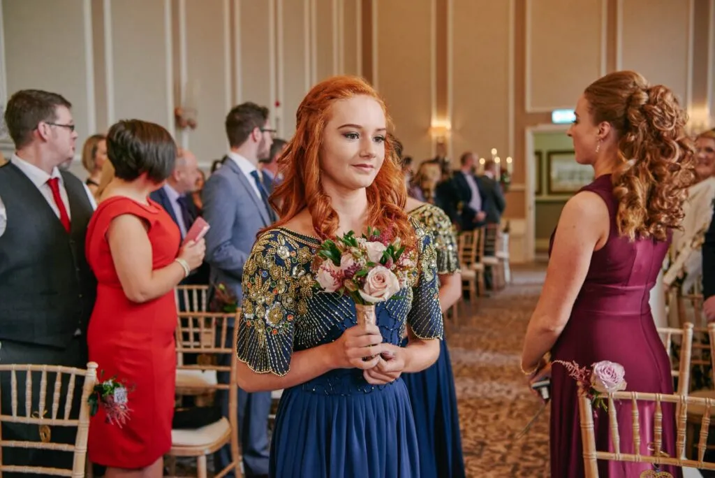 bridesmaid walking down wedding aisle wearing blue sequinned dress