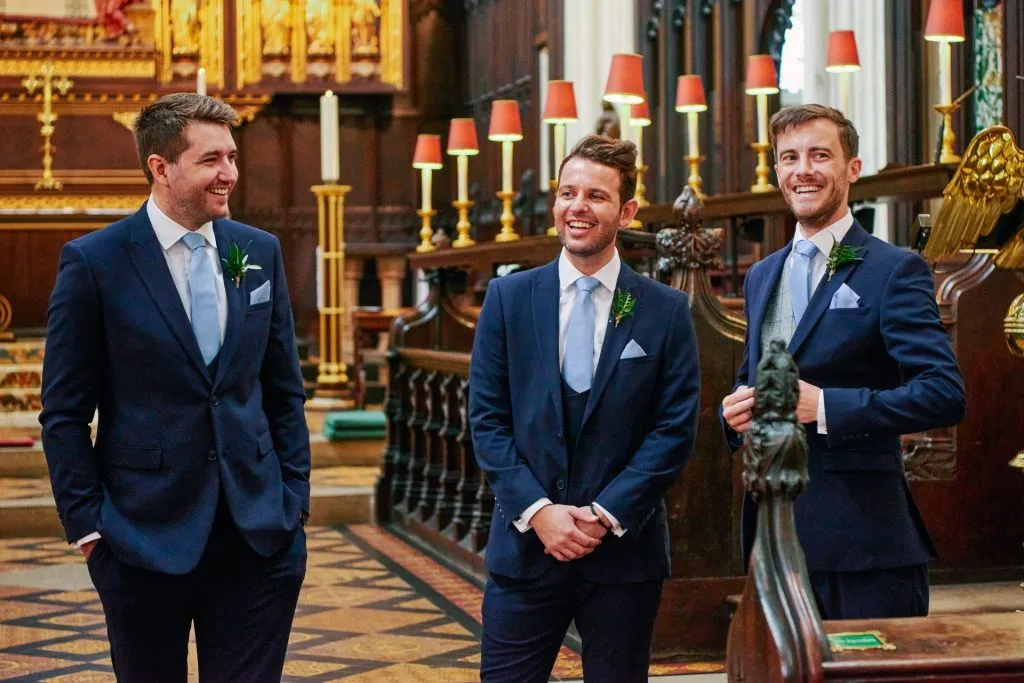 Groom and ushers stood smiling inside St Margaret's Church in central London