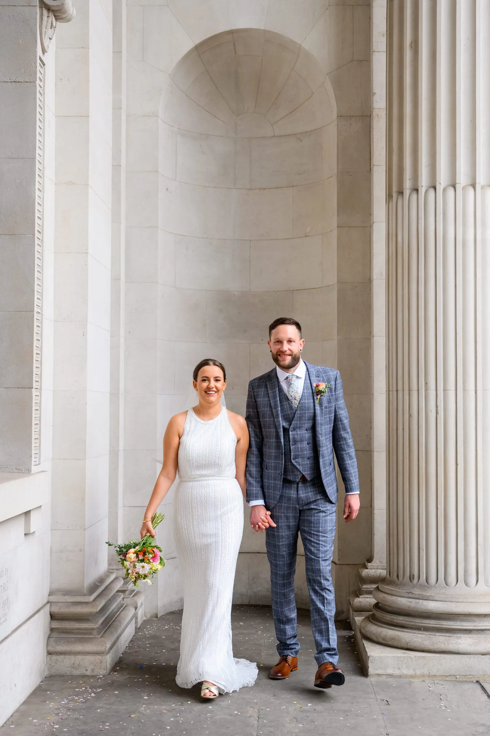 relaxed bride and groom walking under stone archway