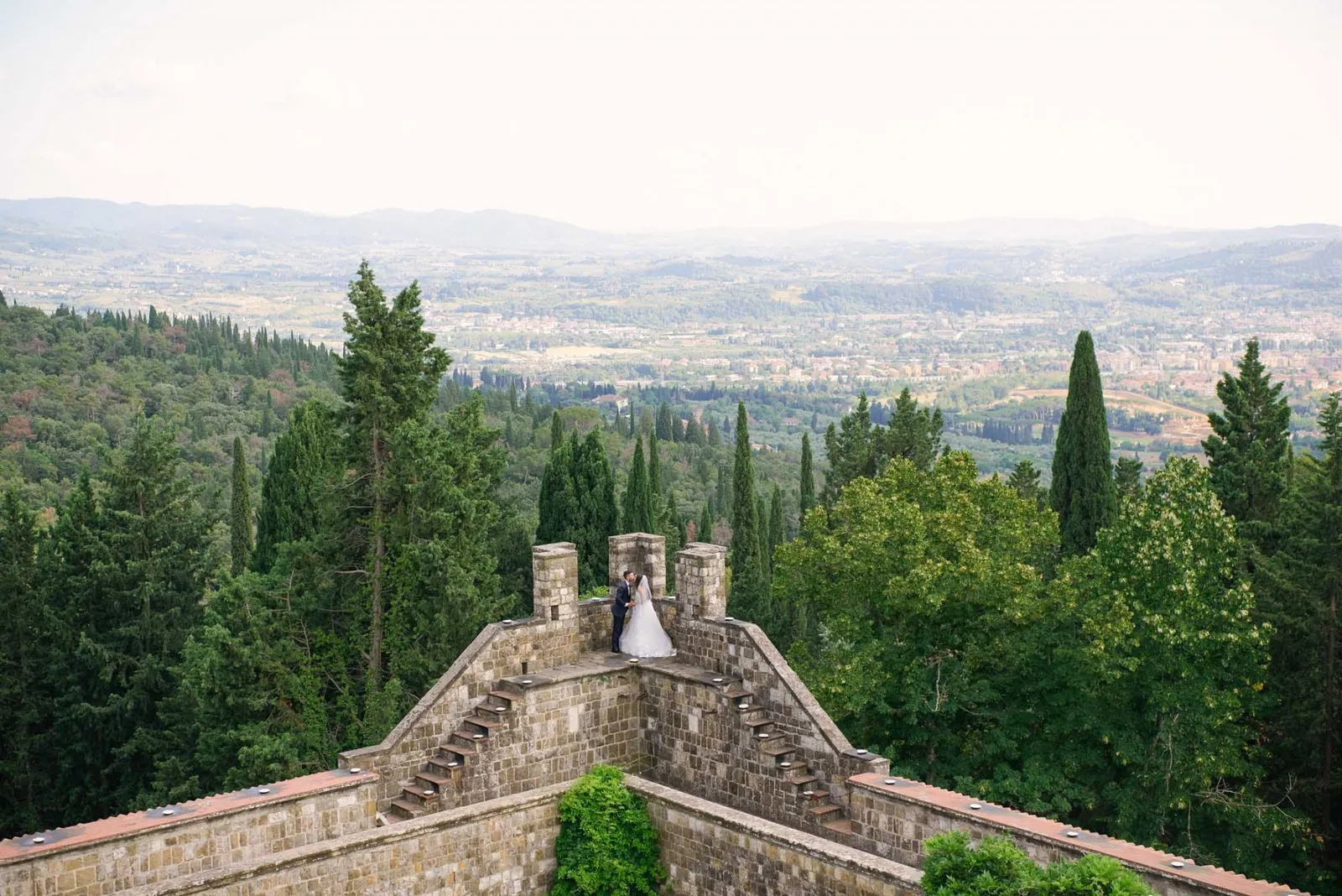 Bride and groom kissing on the edge of their Italian Castle venue overlooking views of Florence