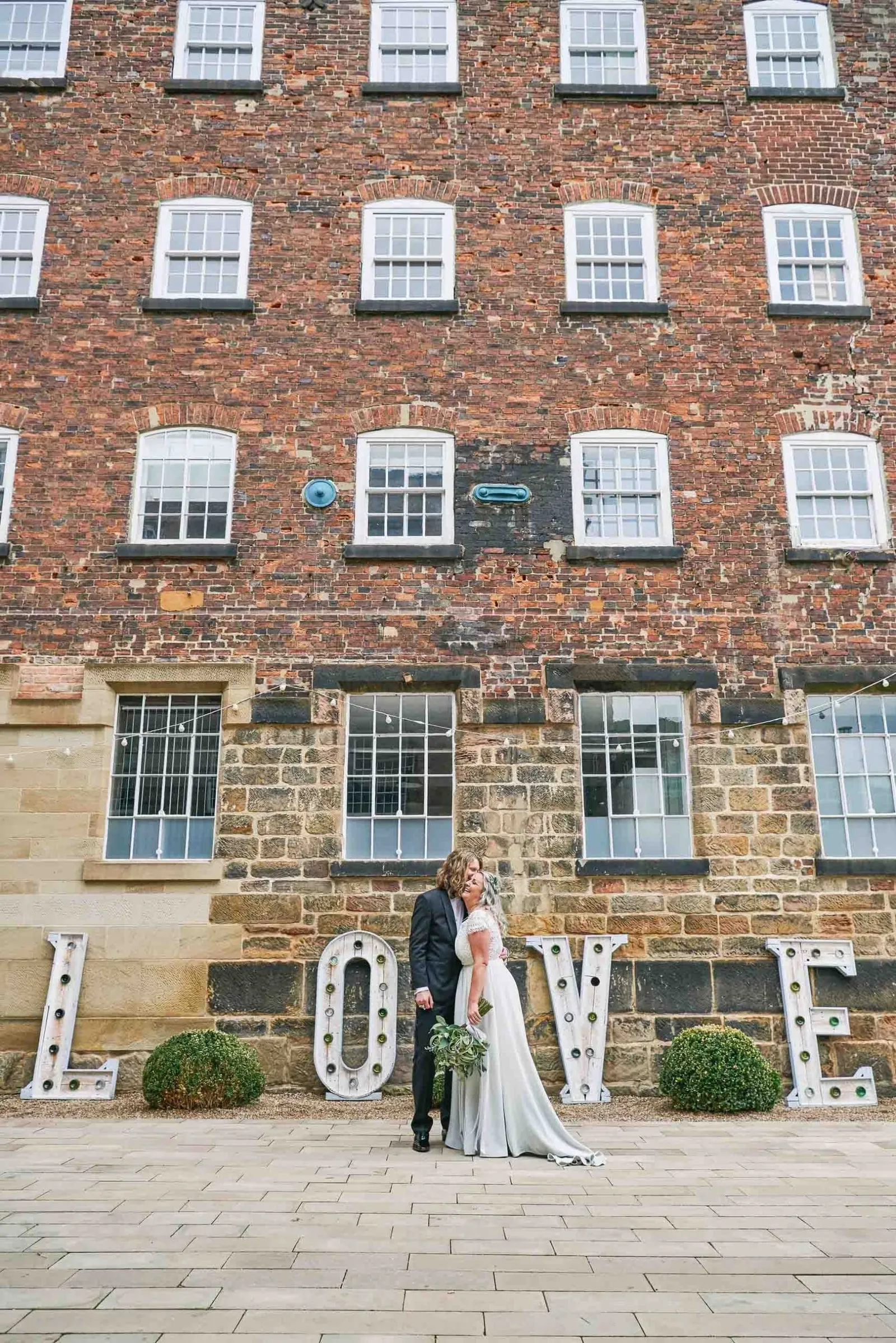 Bride and groom stood in front of The West Mill wedding building