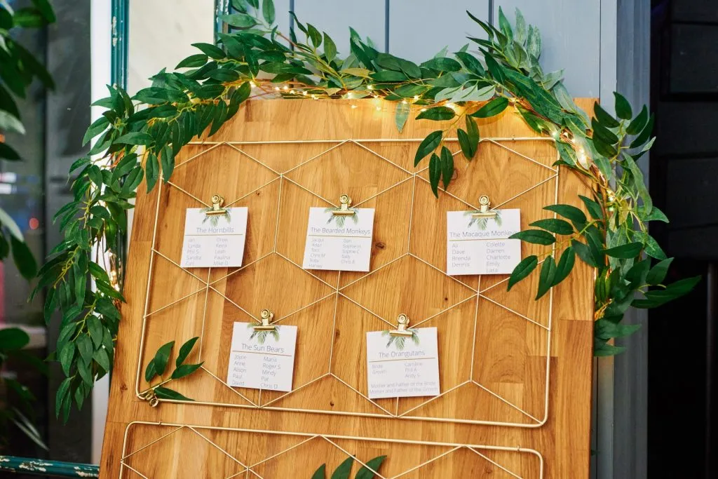 wedding table plan on plank of wood with paper clipped to geometric frame