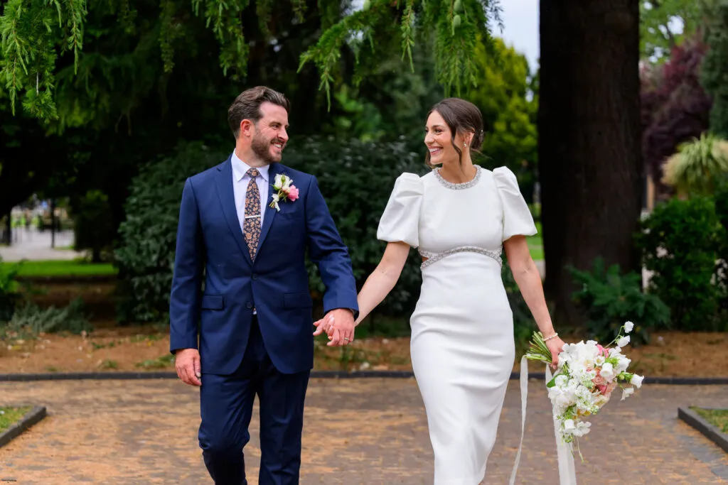 Newly married couple walking through West Bridgford Park after their ceremony