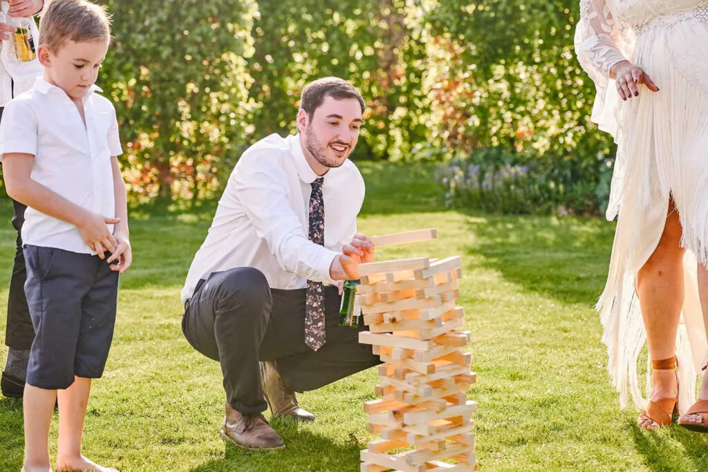 Guest playing garden Jenga during outdoor summer wedding in a garden