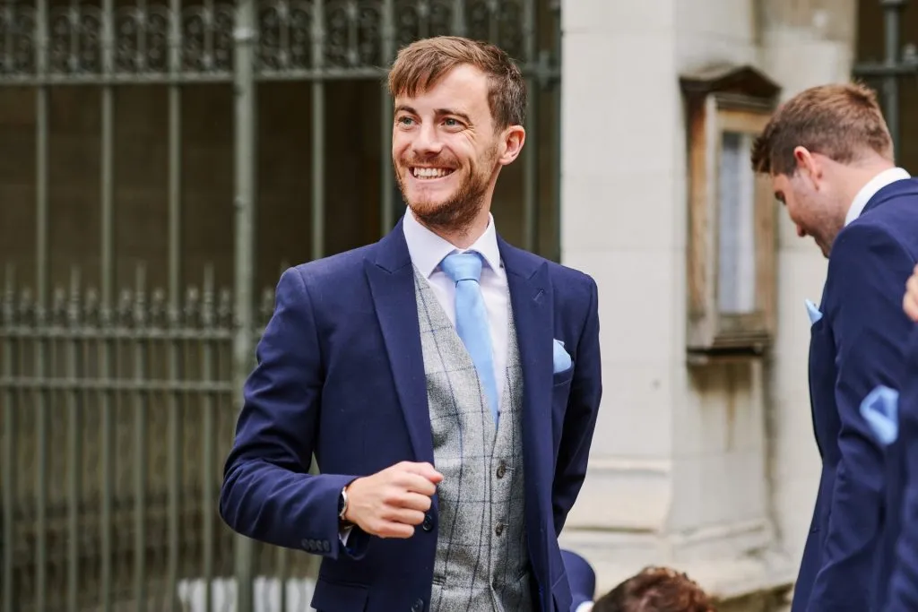 Groom smiling outside of St Margaret's Church in central London 