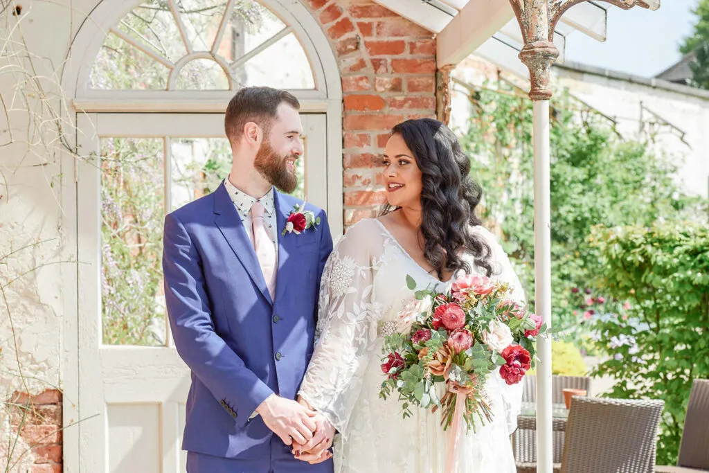 Bride and groom stood under the orangery outside at Pippley Walled Garden