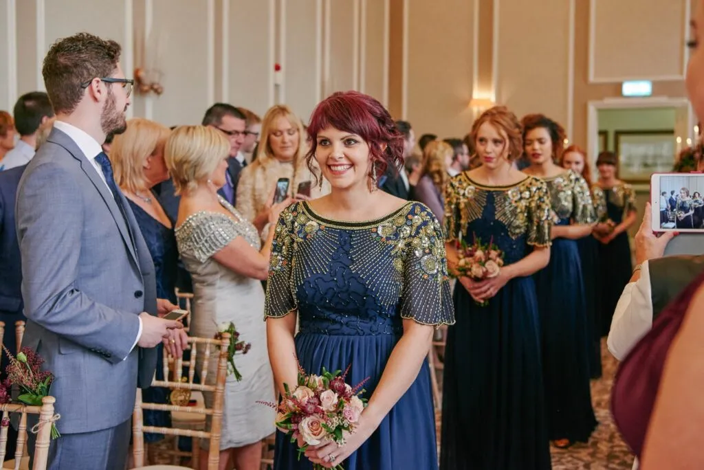 bridesmaid walking down wedding aisle wearing blue sequinned dress