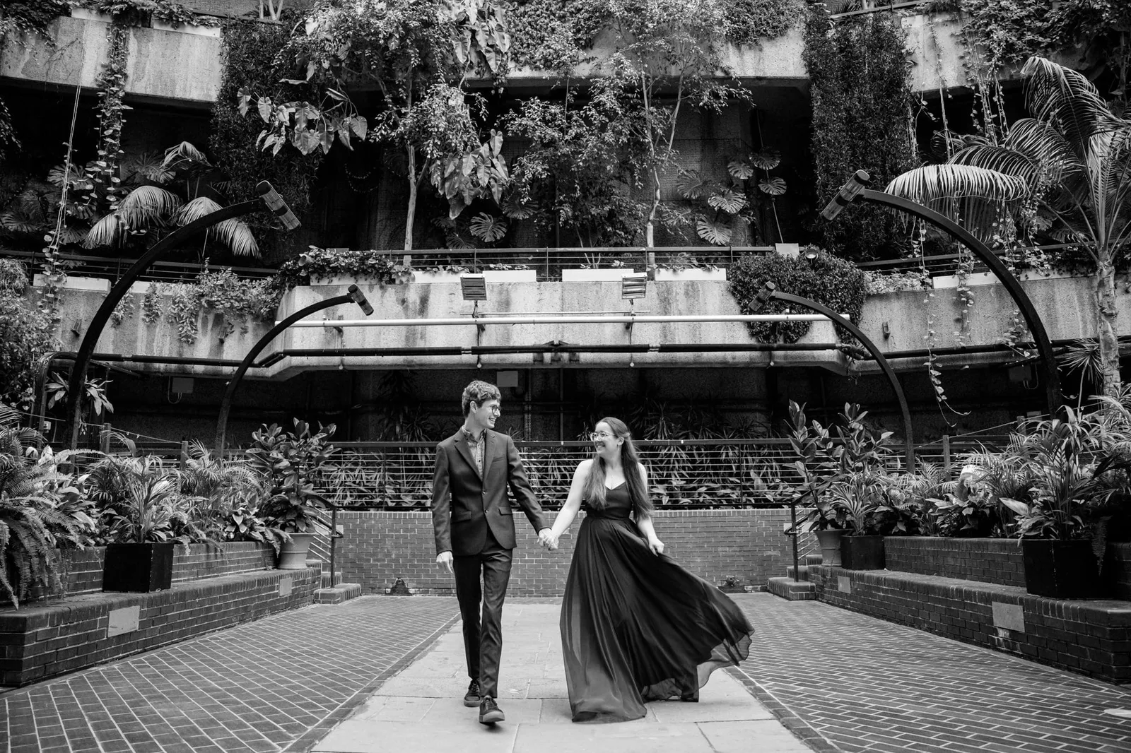 happy couple holding hands whilst walking through the Barbican Conservatory