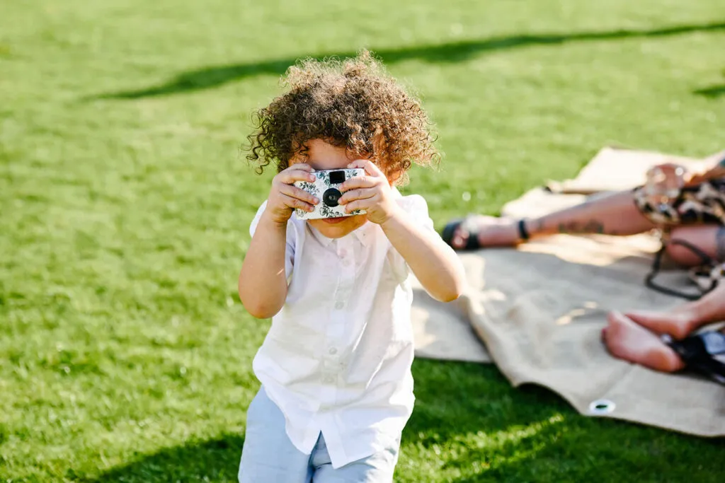 Little boy holiday a disposable camera during summer wedding