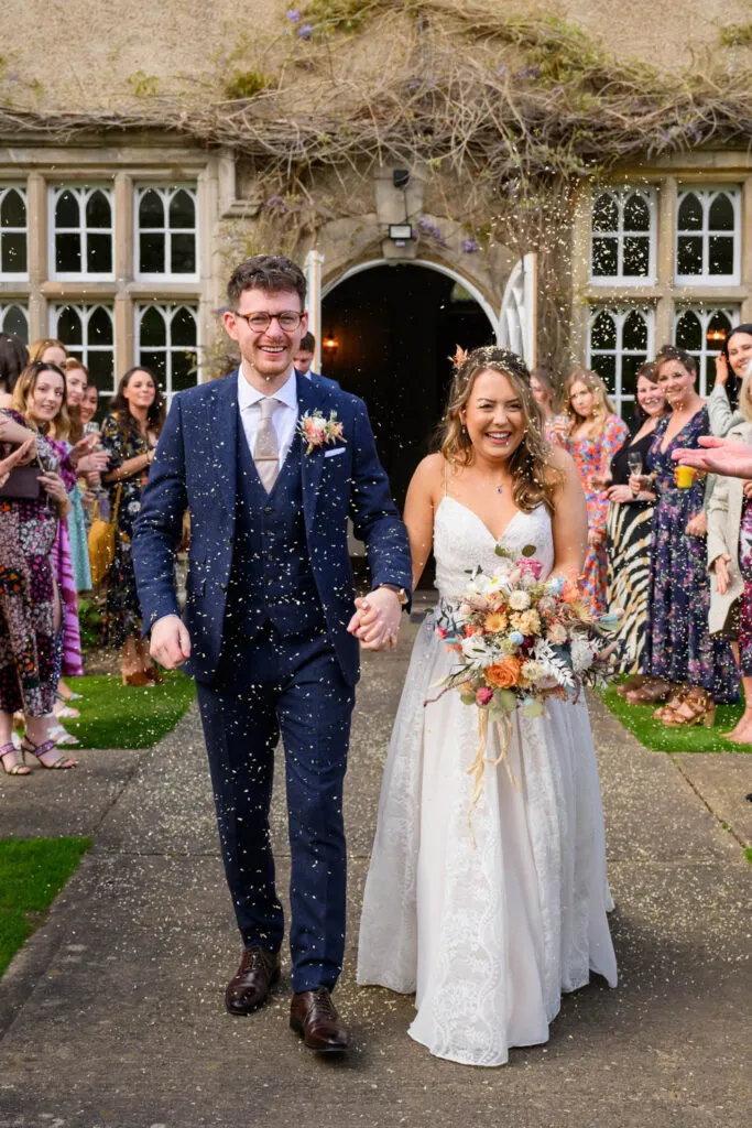 bride and groom walking through confetti at woodborough hall wedding