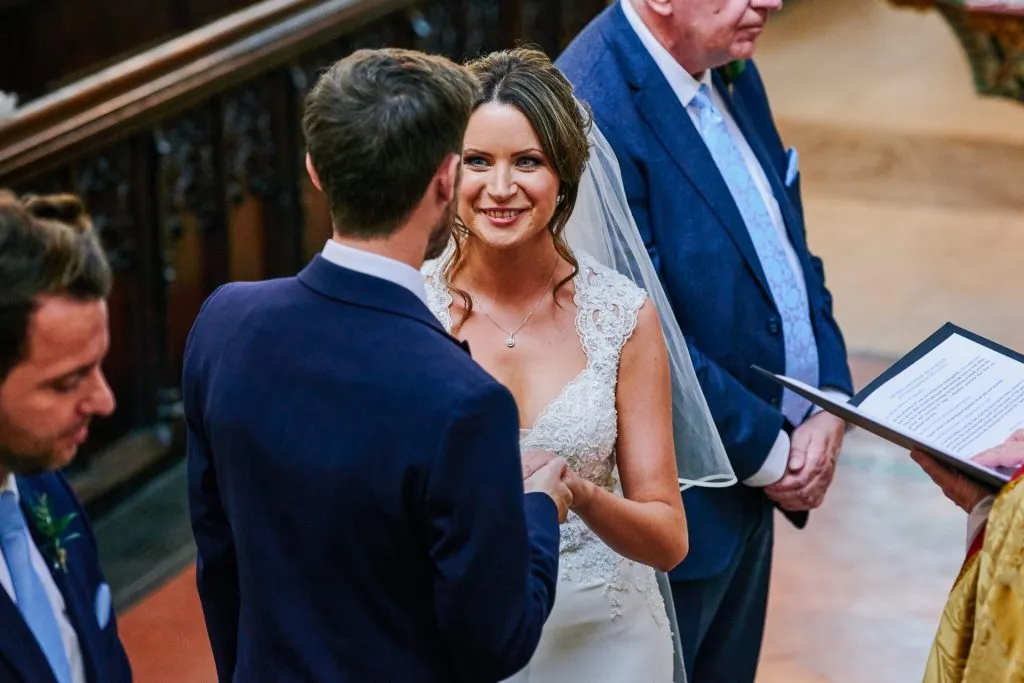 bride and groom smiling at each other during wedding ceremony 