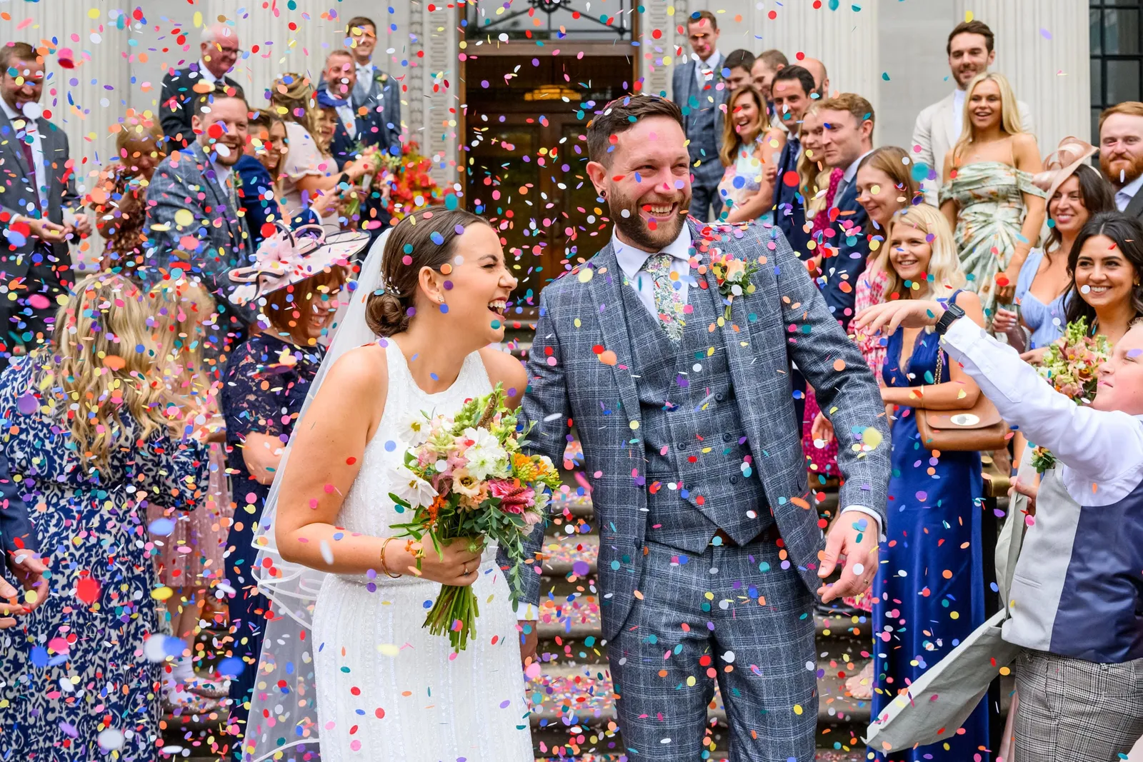 confetti being thrown over happy wedding couple on Marylebone Town Hall steps 