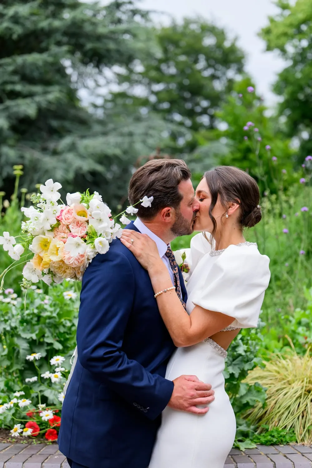 bride and groom kissing in front of flowers during West Bridgford wedding