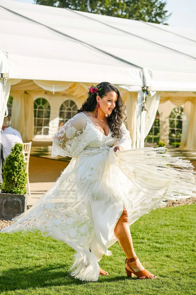 Bride wearing a bohemian-style dress and swishing it around outside in the sun.