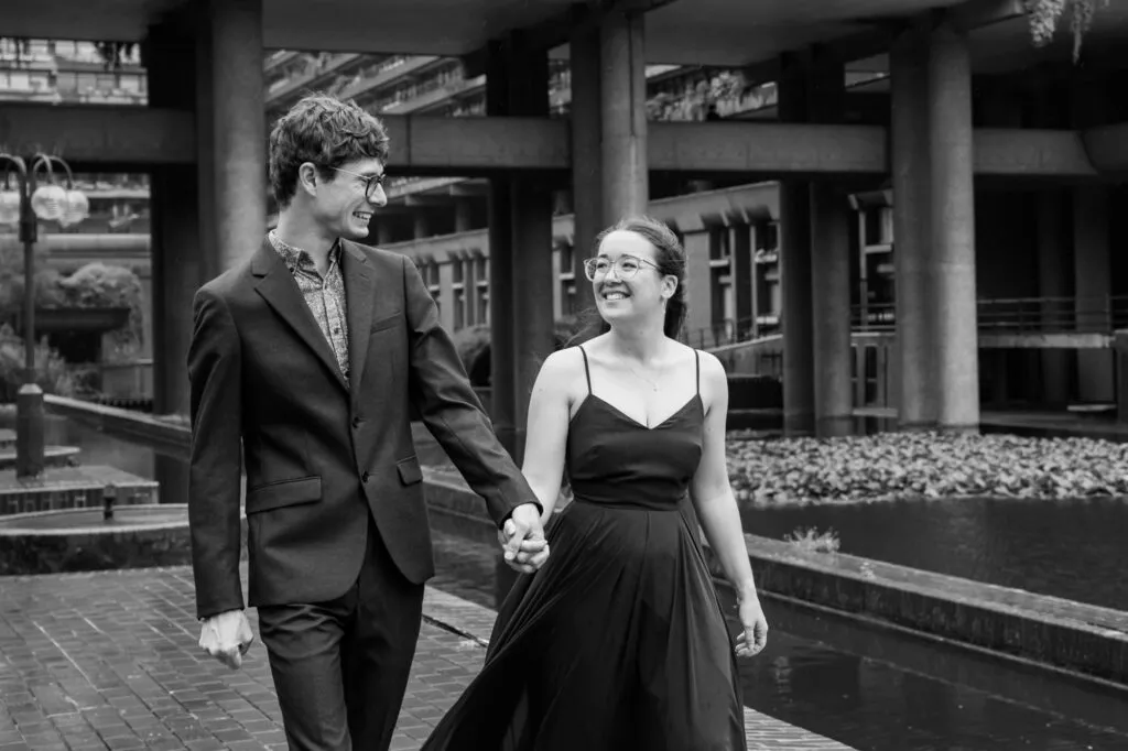 Happy wedding couple holding hands whilst walking outside The Barbican