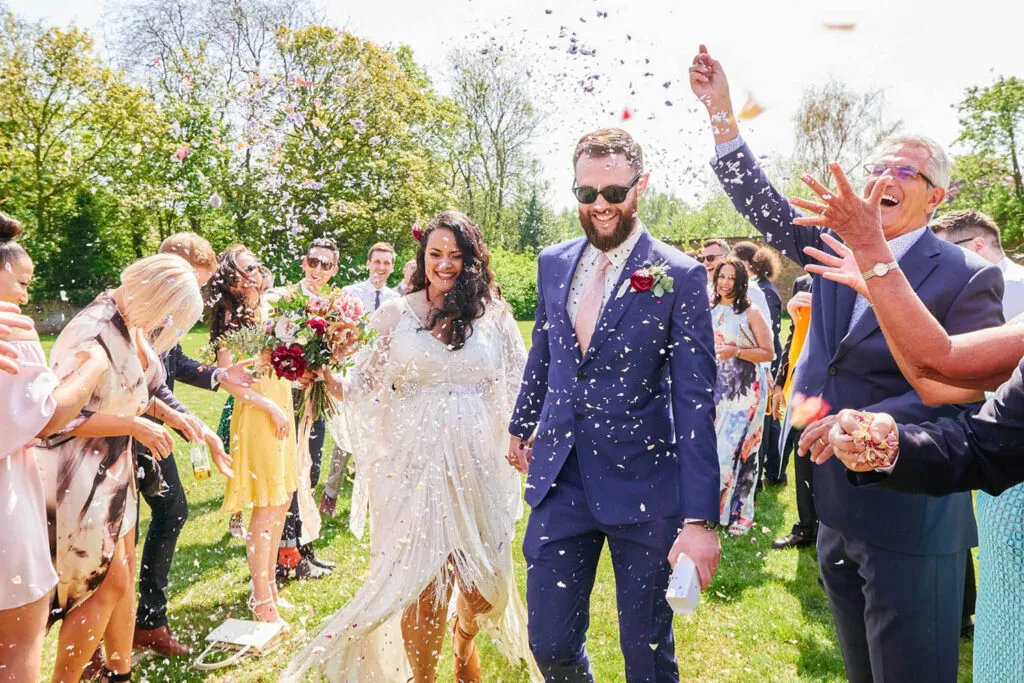 Wedding couple walking through confetti during Pippley Walled Garden wedding