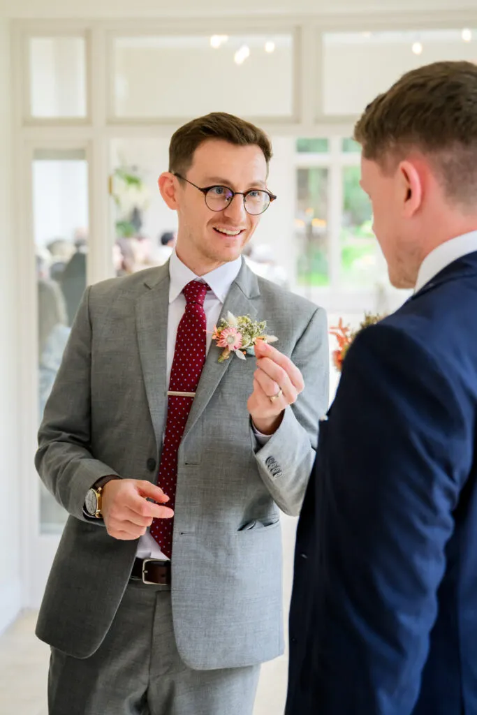 groom preparing boutonniere before ceremony at woodborough hall wedding