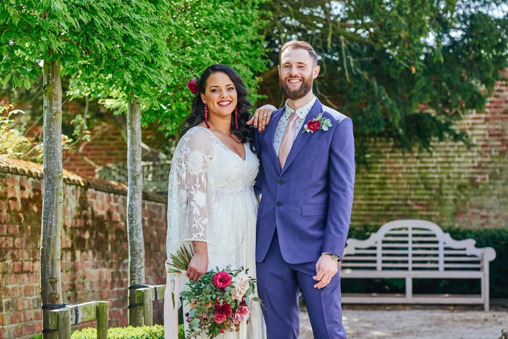 bride and groom smiling together on a tree-lined path surrounded by greenery.