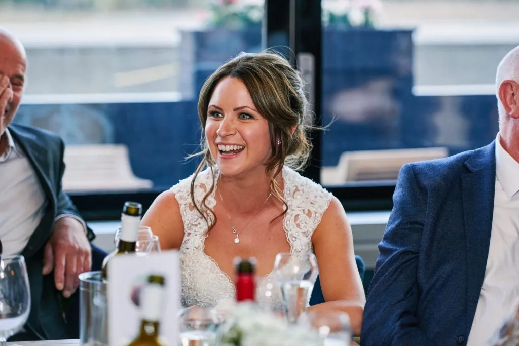 Happy bride laughing during wedding speeches at The Oyster Shed