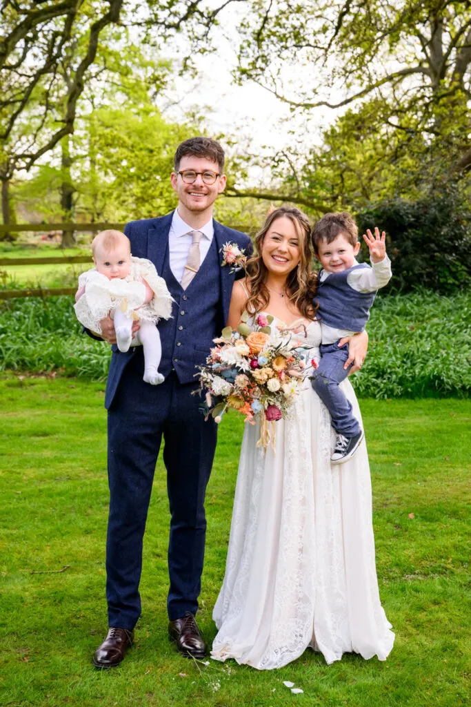 bride and groom with children in gardens at woodborough hall wedding