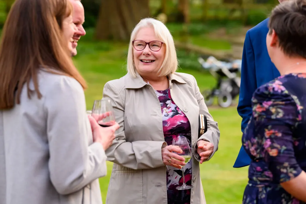 wedding guests laughing together in the gardens at woodborough hall