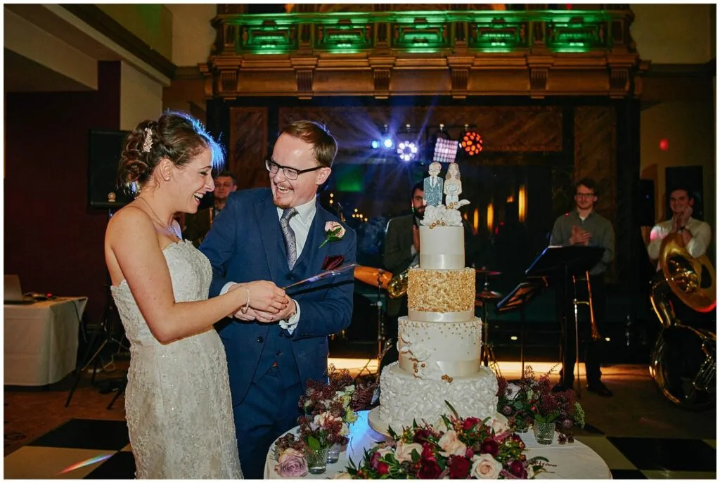 Bride and groom cutting the cake during their fun winter wedding reception