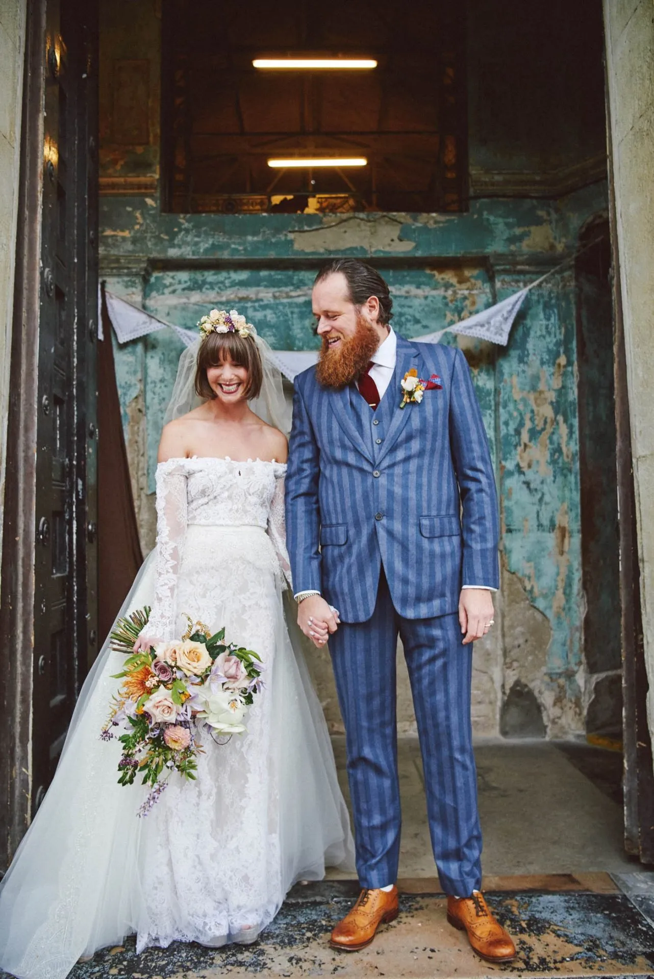 bride and groom laughing together in front of rustic entrance at the Asylum venue in London
