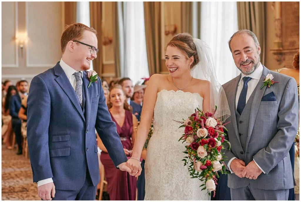 bride and groom smiling as they great each other during wedding ceremony