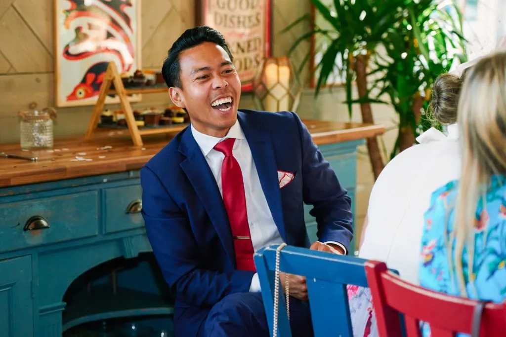 male wedding guest laughing whilst sat down for dinner at the Oyster Shed