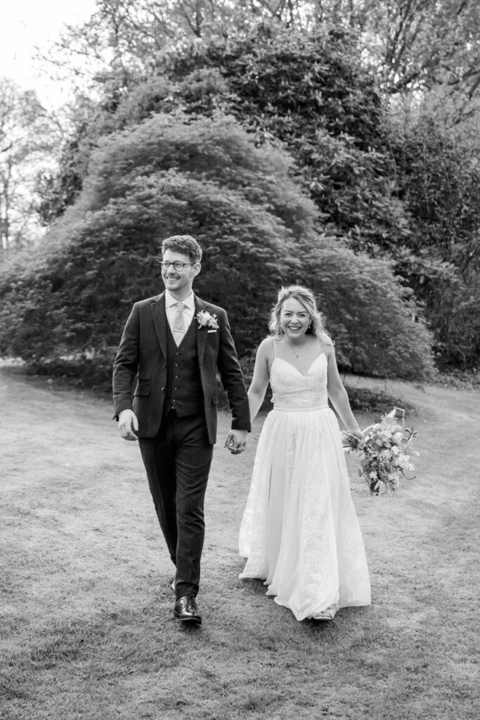 black and white portrait of bride and groom walking in woodborough hall gardens