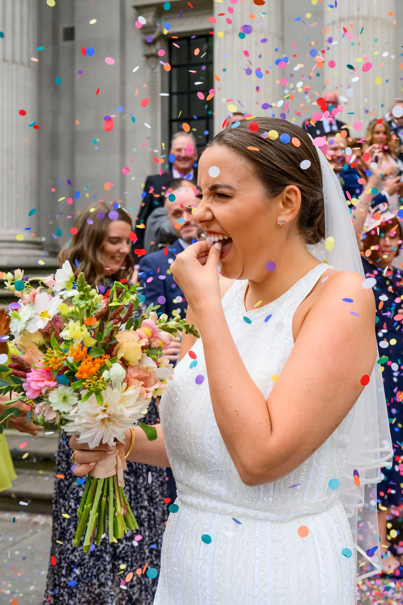 Bride picking confetti out of her mouth at Marylebone Town Hall