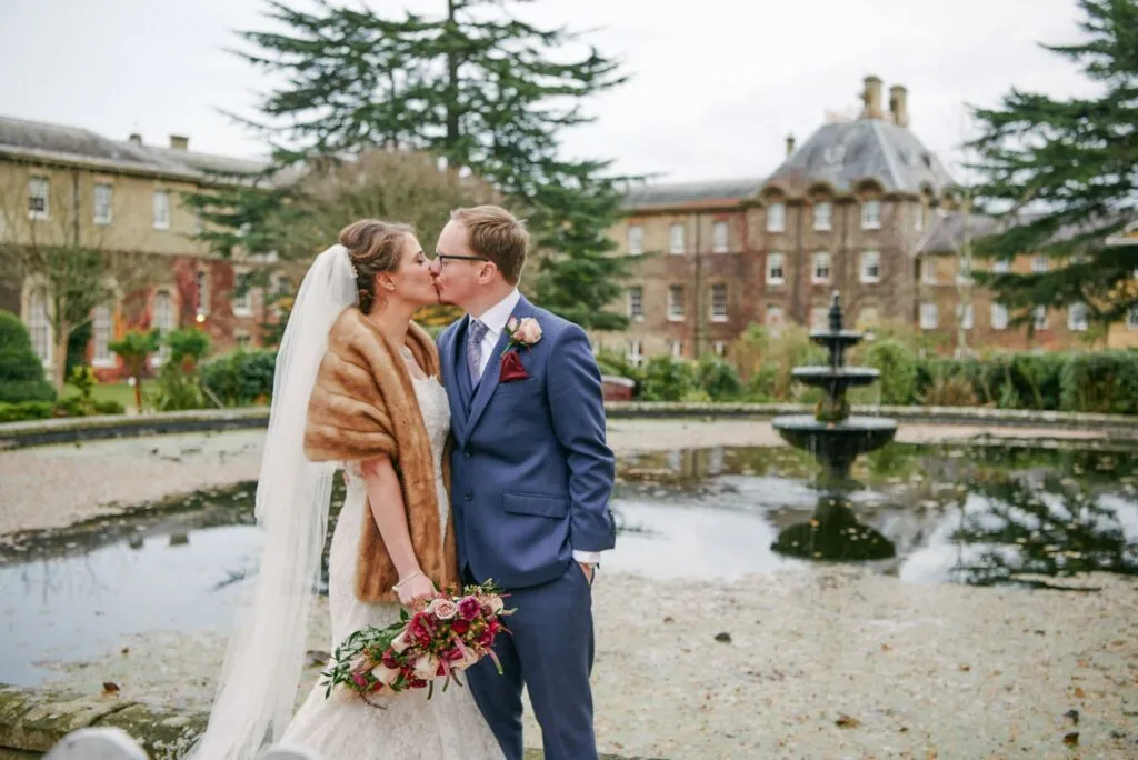 Bride and groom kissing during winter wedding at De Vere Beaumont Estate in Windsor