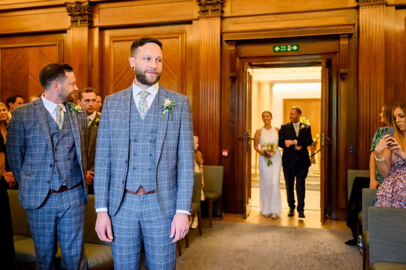 Groom waiting as bride and father walk down wedding asile