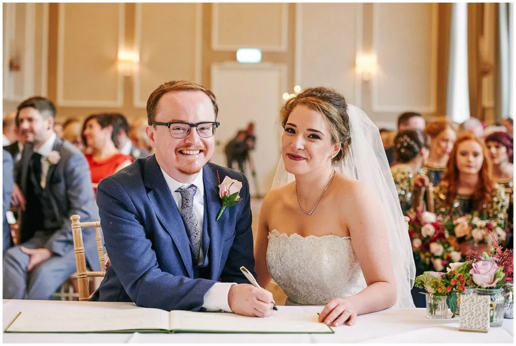 Bride and groom signing the register during their wedding ceremony at Beaumont Estate
