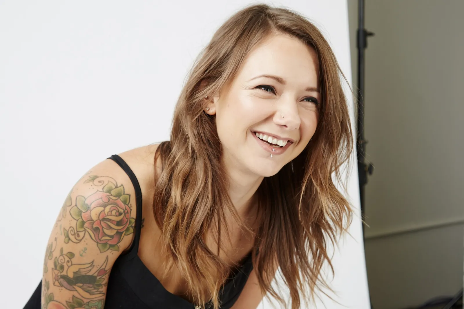 Tattooed female wedding photographer laughing in a photo studio
