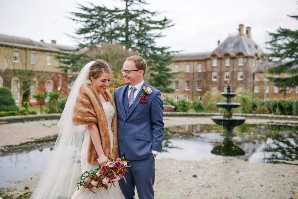 Bride and groom laughing together during winter wedding at De Vere Beaumont Estate in Windsor