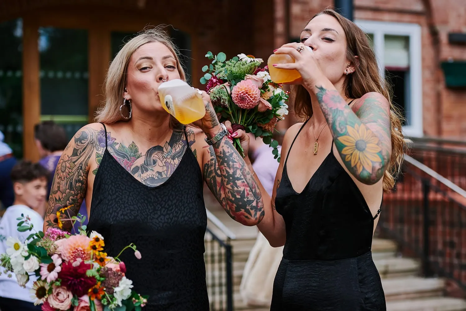 tattooed bridesmaids wearing black dresses drinking cider