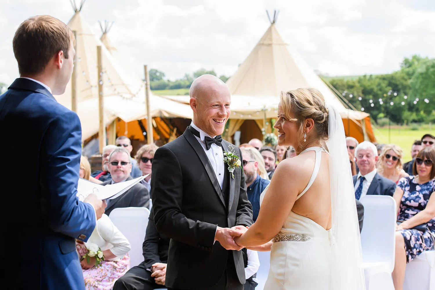 bride and groom holding hands during outside tipi ceremony in Nottingham