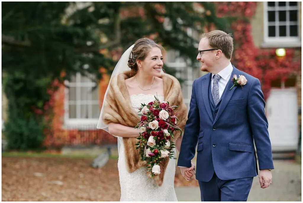 bride and groom smiling whilst walking outside during fun winter wedding
