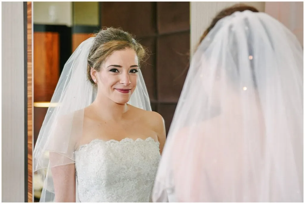 Bride smiling whilst looking in a mirror during bridal prep