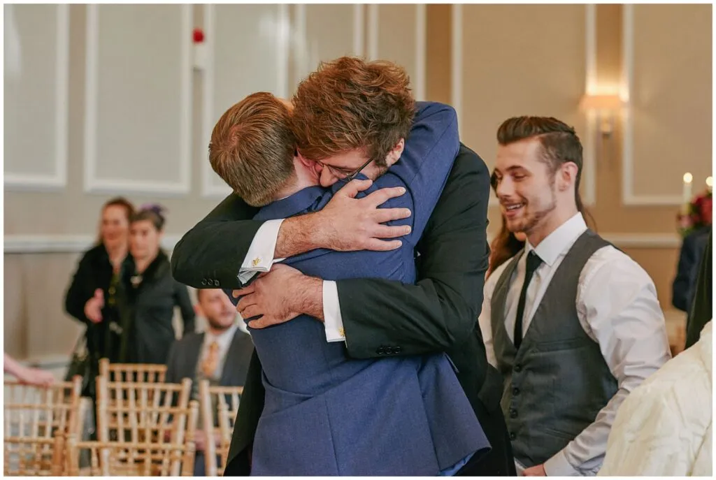 groom hugging a wedding guest during his ceremony at the Beaumont Estate