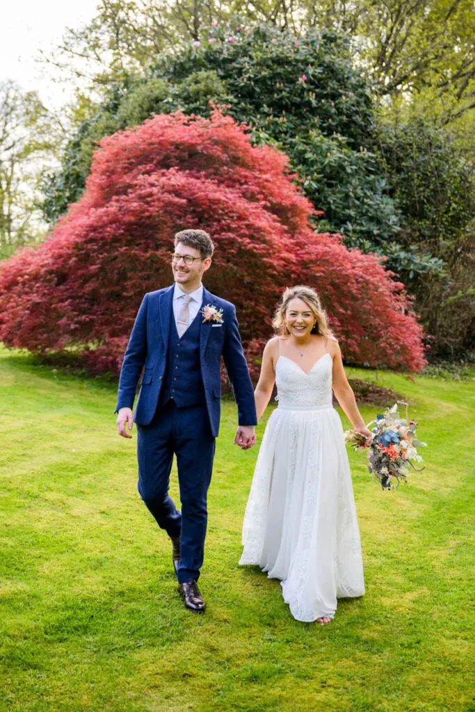 bride and groom walking in gardens at woodborough hall wedding venue