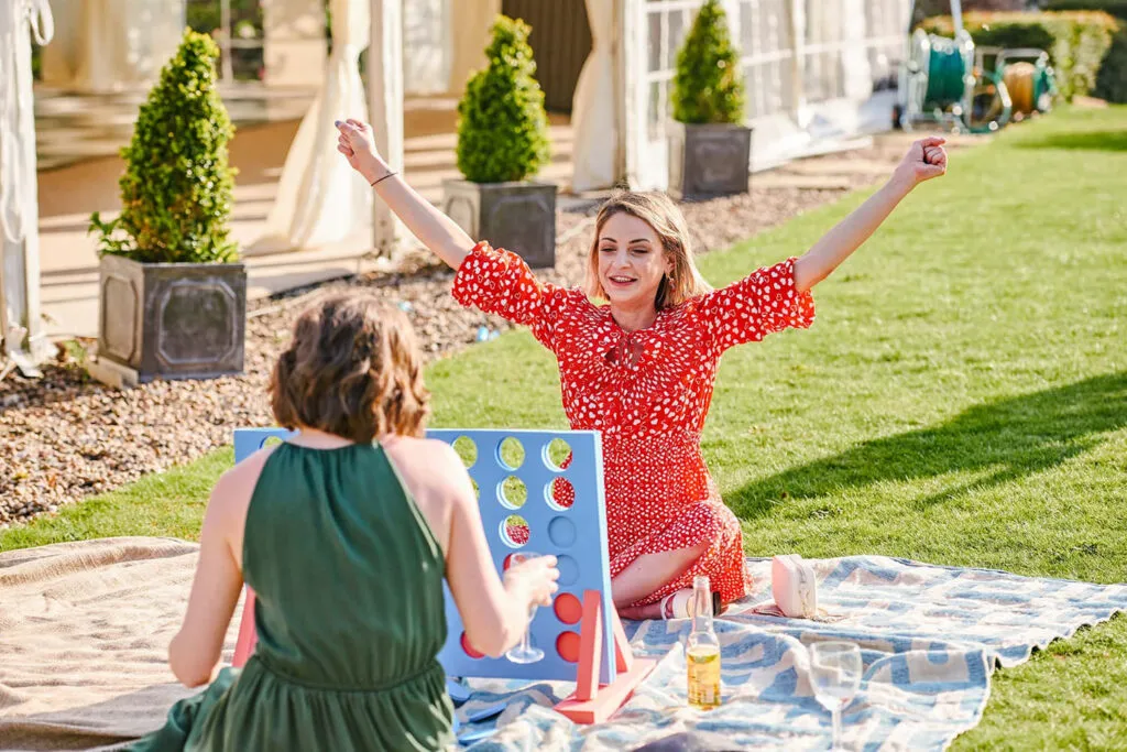 Guests playing large Connect Four during outdoor summer wedding in a garden