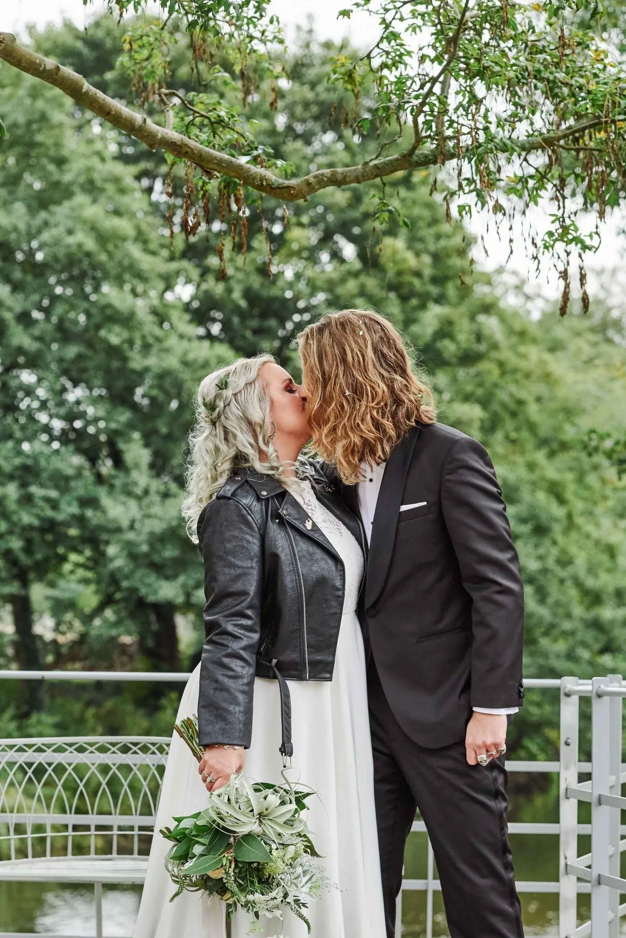 Rock n Roll Bride and groom kissing next to the river at the West Mill in Derbyshire