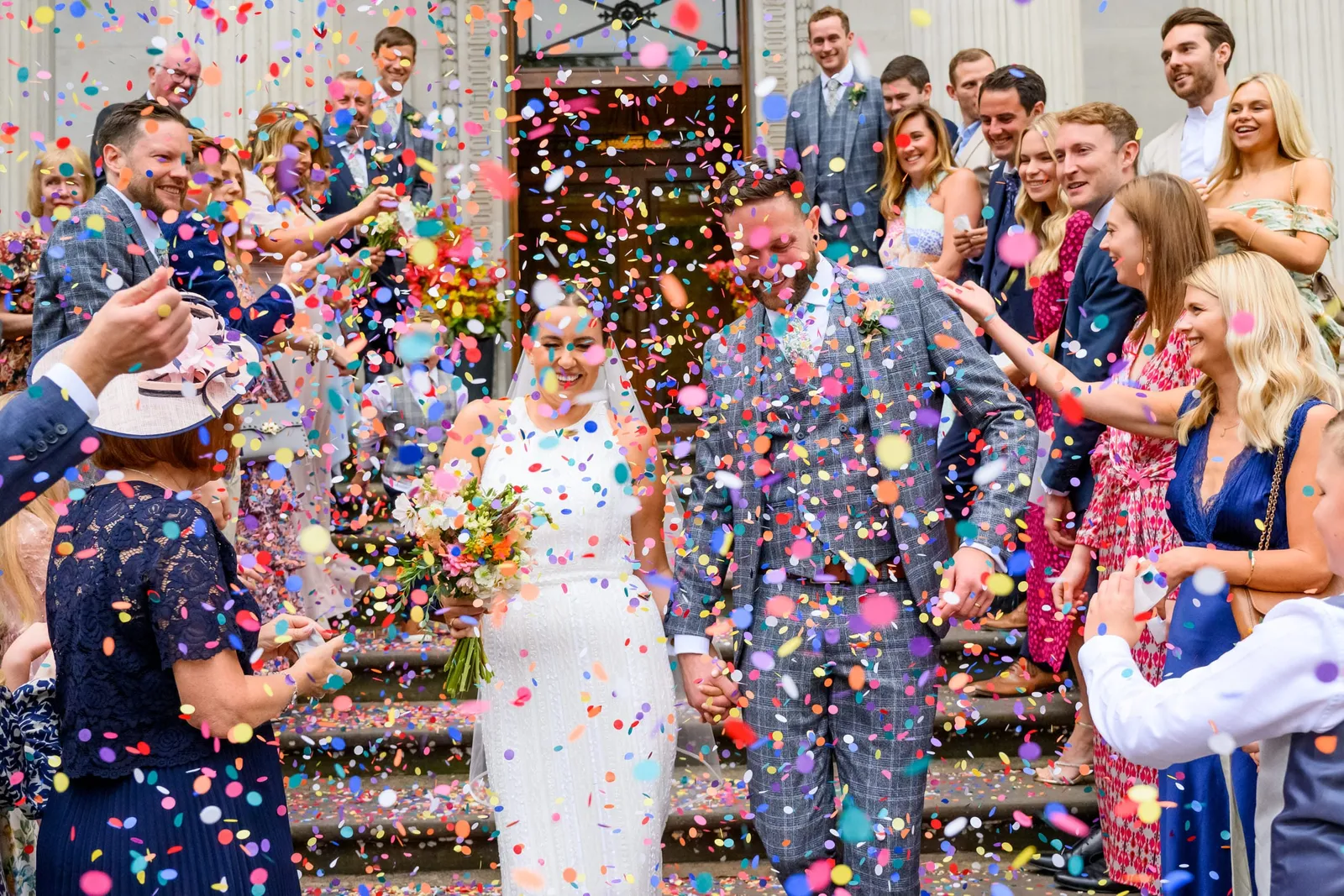 Bride and groom walking through colourful confetti outside town hall