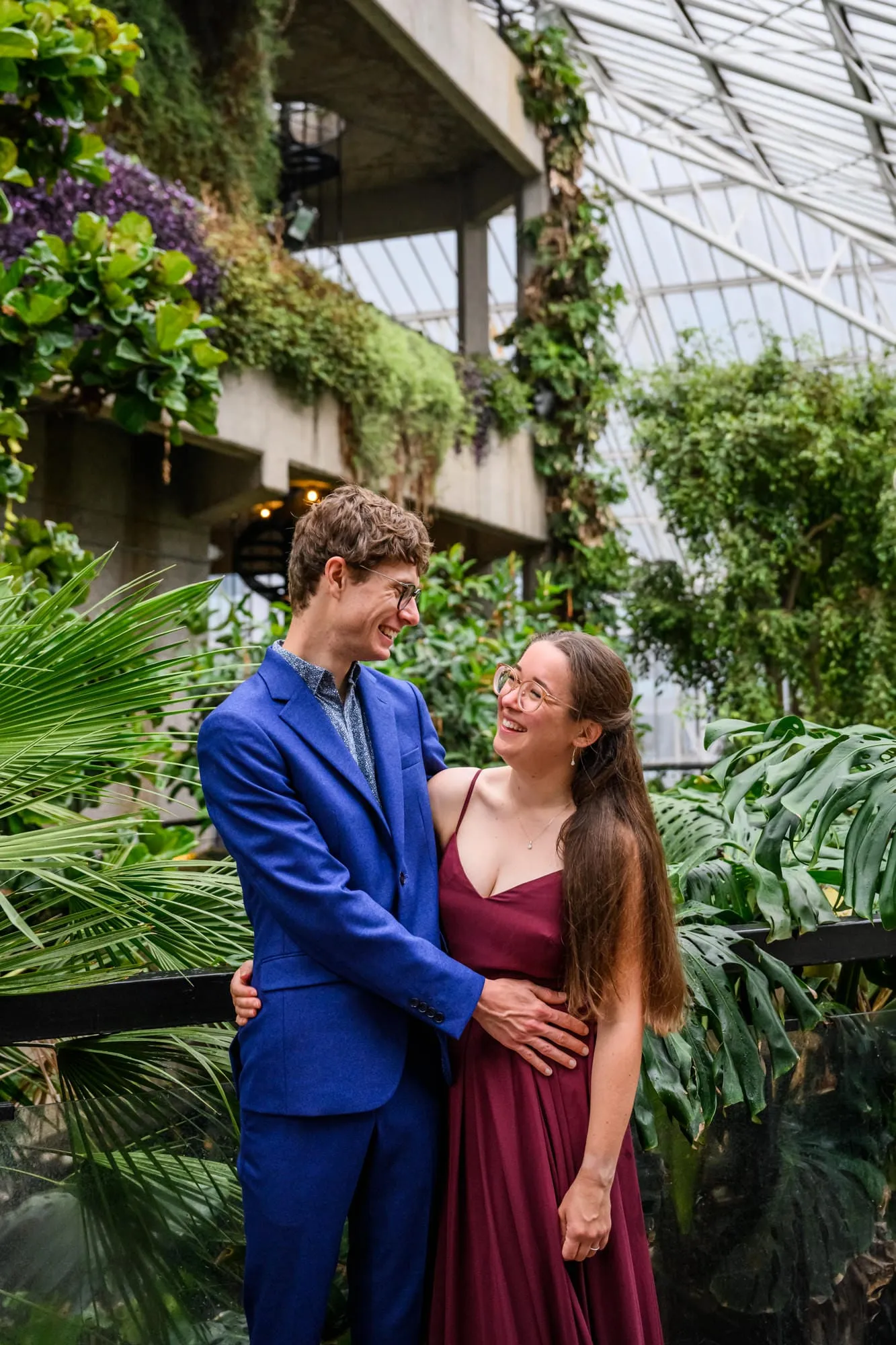 wedding couple smiling together surrounded by plants inside the barbican conservatory