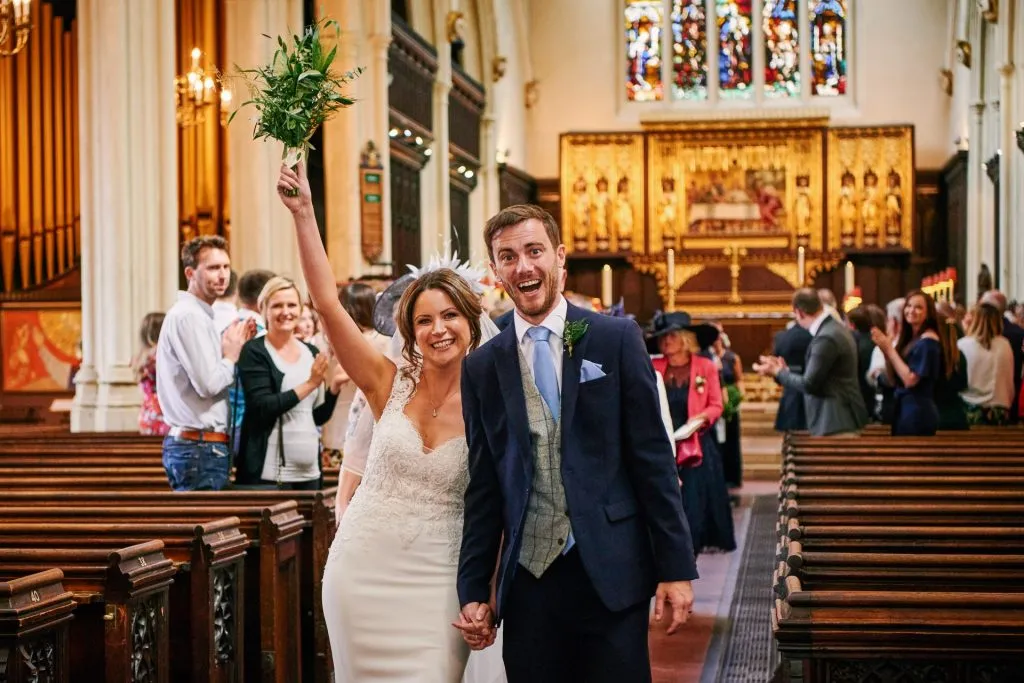 Bride and groom walking back down the aisle together in St Margret's Church. 