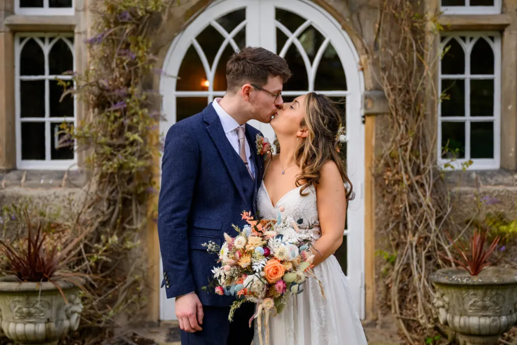 bride and groom kissing outside the entrance at woodborough hall wedding venue